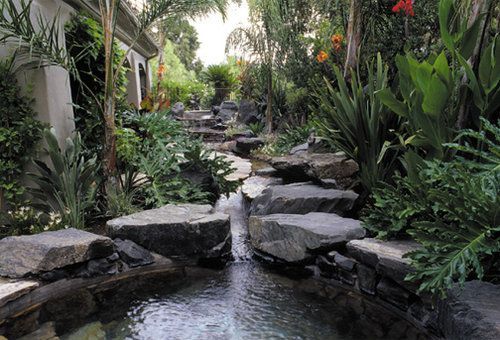 A waterfall is surrounded by rocks and plants in a garden.