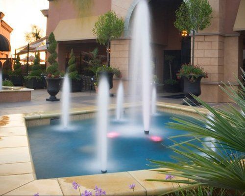 A fountain is spraying water into a pool in front of a building