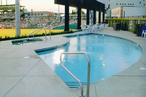 A large swimming pool in front of a baseball field