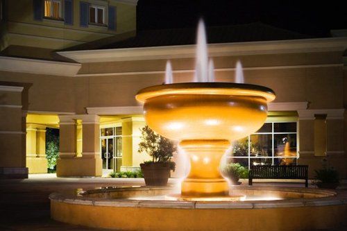 A large fountain is lit up at night in front of a building.