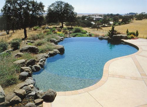 A large swimming pool surrounded by rocks and grass