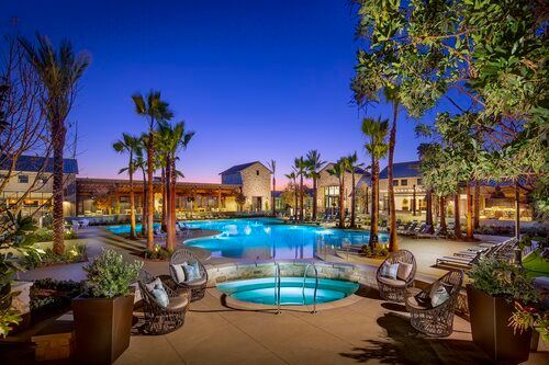 A large swimming pool surrounded by palm trees at night.