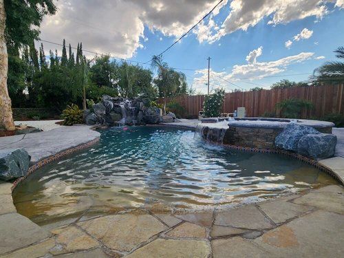 A large swimming pool with a waterfall in the backyard.