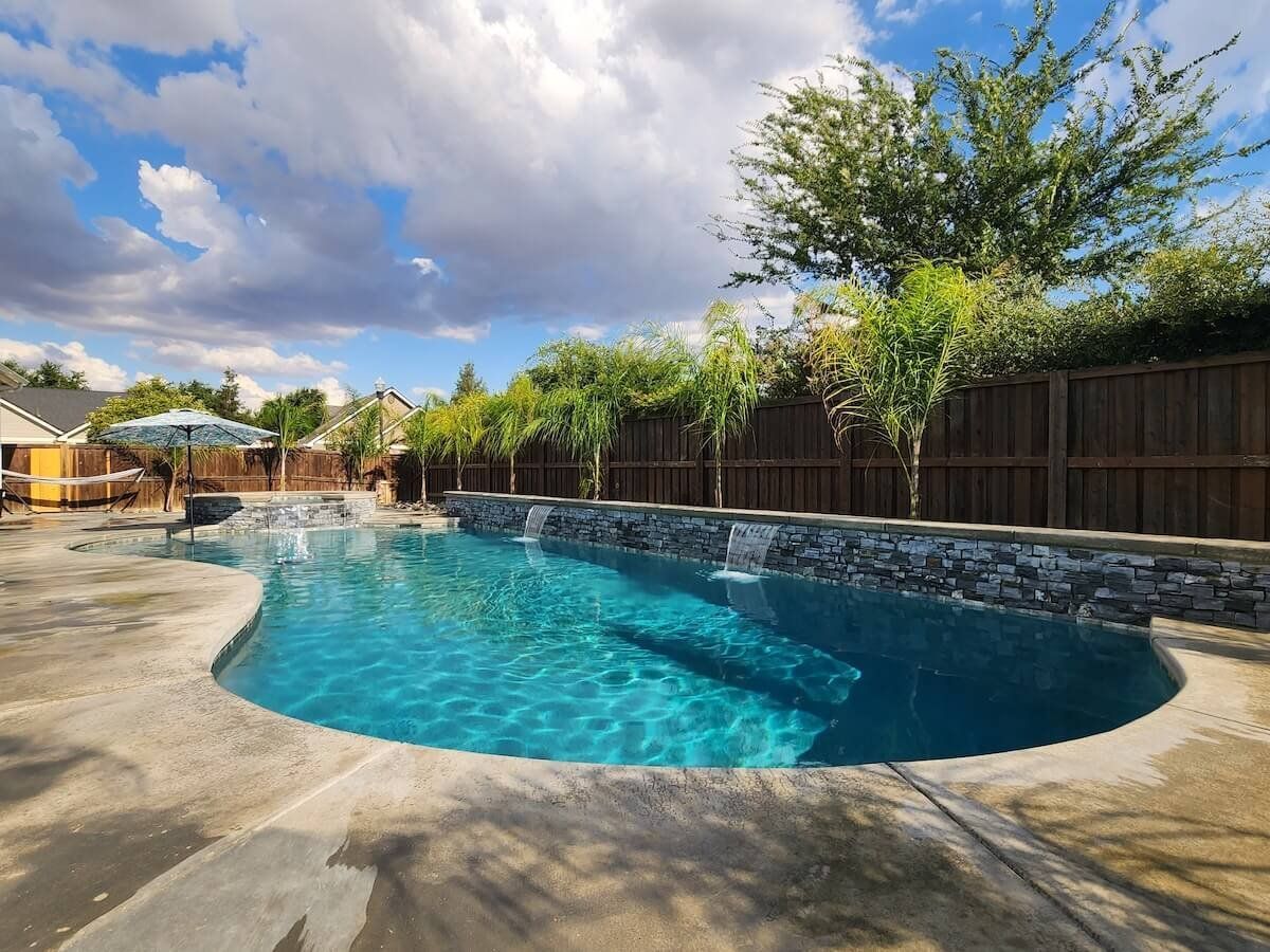 A water fountain is surrounded by a stone wall in a park.