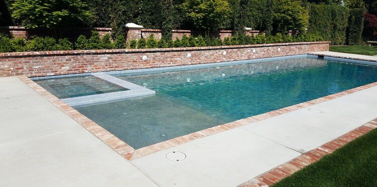 A large swimming pool with a brick wall surrounding it.