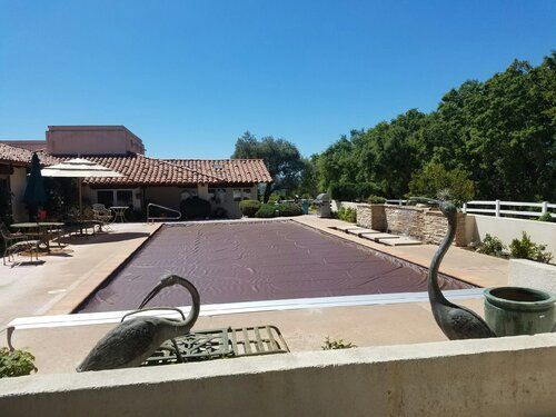 A large swimming pool with a house in the background