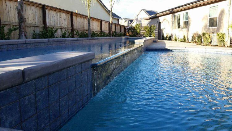 A large swimming pool is surrounded by a fence and houses.