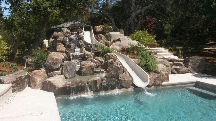 A swimming pool with a water slide and a waterfall