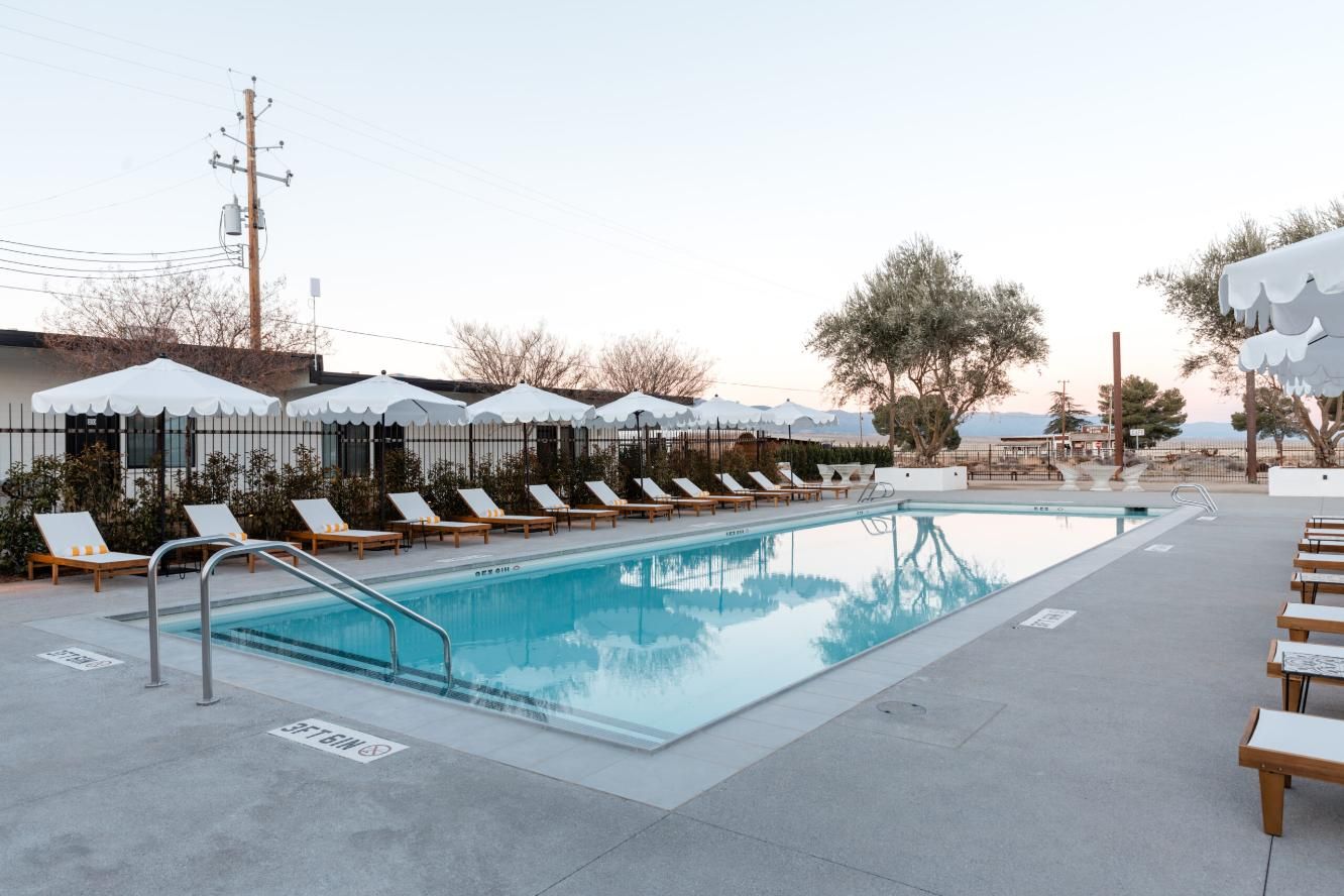 A large swimming pool surrounded by chairs and umbrellas.
