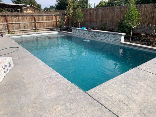 A large swimming pool with a wooden fence in the background.