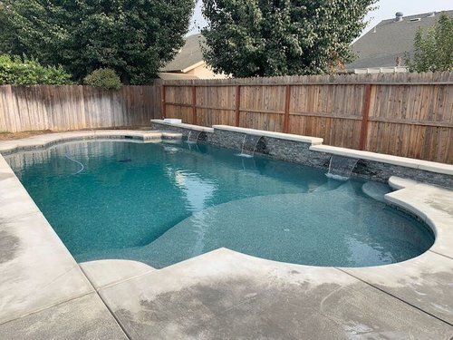 A large swimming pool surrounded by a wooden fence in a backyard.