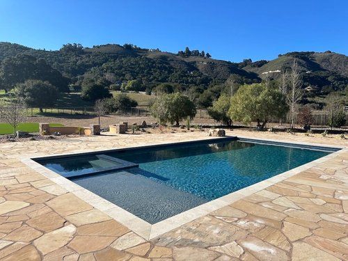 A large swimming pool is surrounded by trees and mountains.