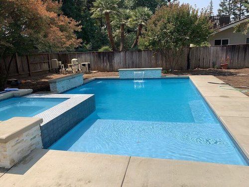There is a large swimming pool in the backyard of a house.