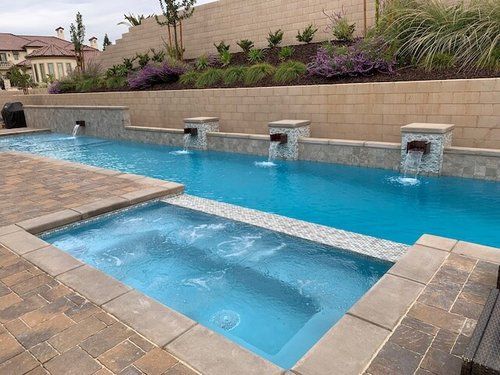 A large swimming pool with a hot tub next to it.