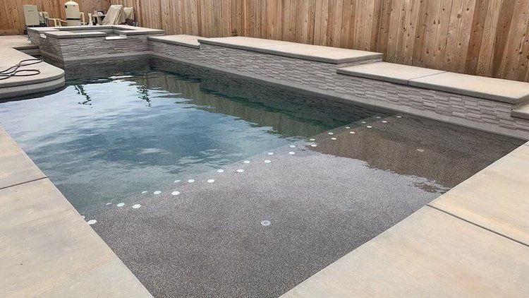 A large swimming pool is surrounded by a wooden fence.