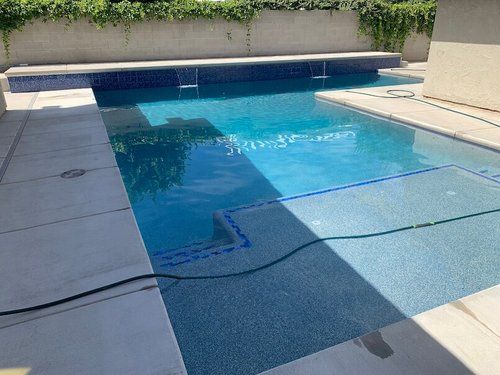 A large swimming pool with a hose attached to the side of it.