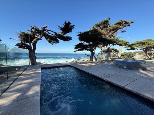 A large swimming pool with a view of the ocean and trees in the background.