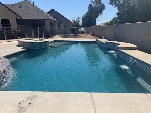There is a large swimming pool in the backyard of a house.