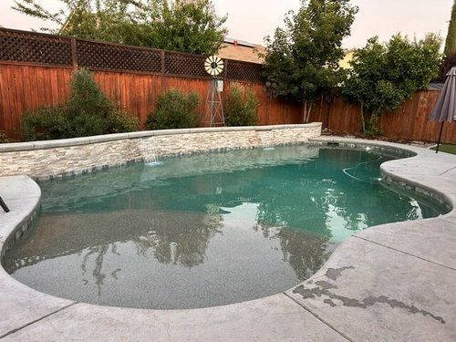 A large swimming pool is lit up at night with blue lights.