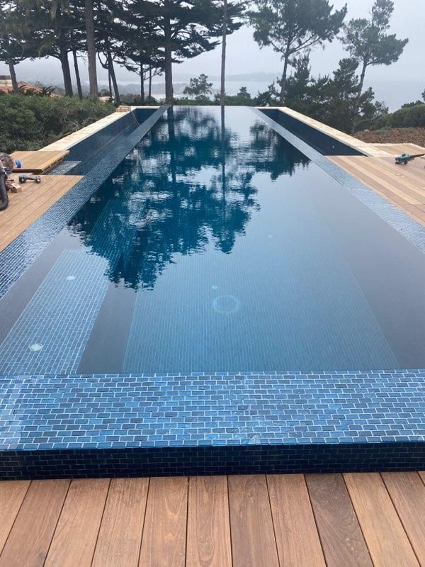 A large swimming pool surrounded by trees and a wooden deck