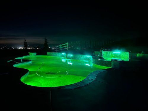 A swimming pool is lit up with green lights at night.