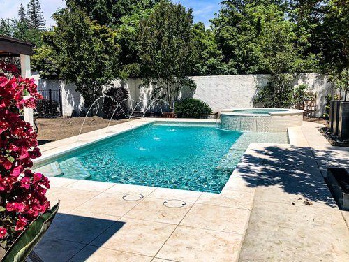 There is a large swimming pool in the backyard of a house.
