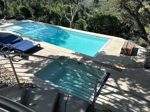 A large swimming pool surrounded by trees on a hillside.