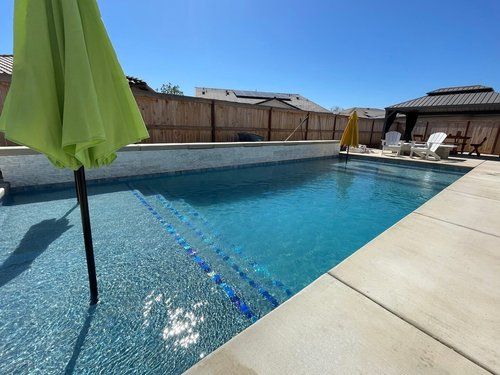 A large swimming pool with a green umbrella in the foreground.