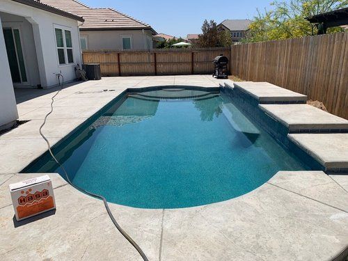 A large swimming pool with a diving board in front of a house