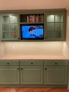 A kitchen with green cabinets and a flat screen tv.