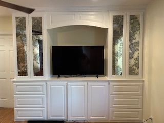 A living room with white cabinets and a flat screen tv.
