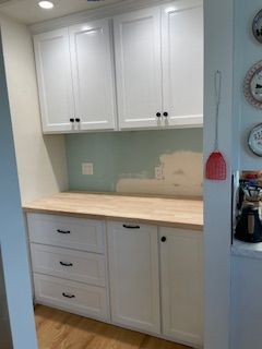 A kitchen with white cabinets and wooden counter tops.