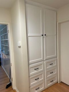 A white cabinet with drawers in a hallway next to a door.