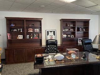A large office with a desk , chairs and shelves