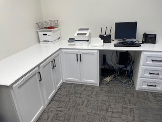 A small office with a desk , computer , printer , and telephone.