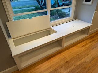 A window seat with a storage space underneath it in a living room.