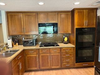 A kitchen with wooden cabinets , granite counter tops , stainless steel appliances and a stove.