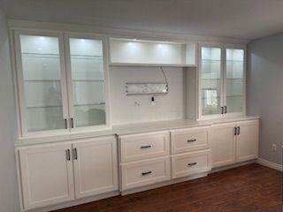 A living room with white cabinets , drawers , and glass doors.