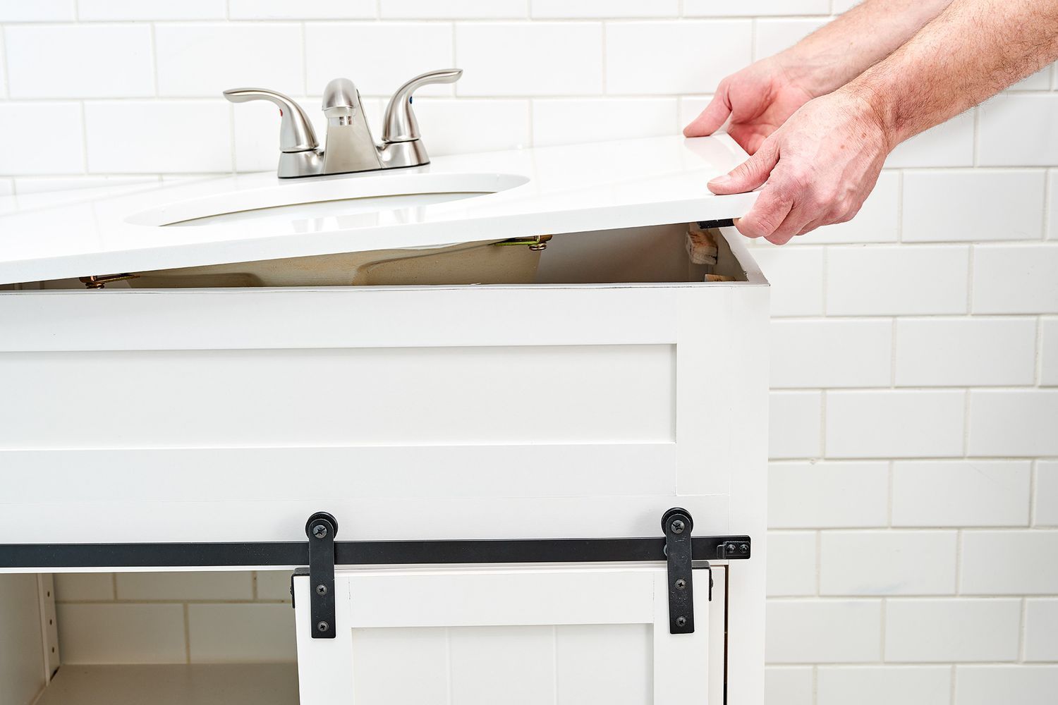 A person is installing a sliding barn door on a bathroom vanity.