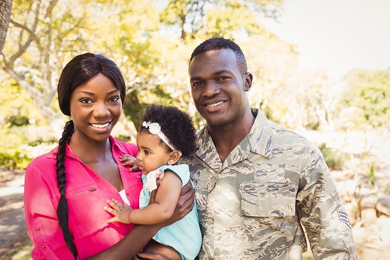 a man in a military uniform holds a woman and a baby