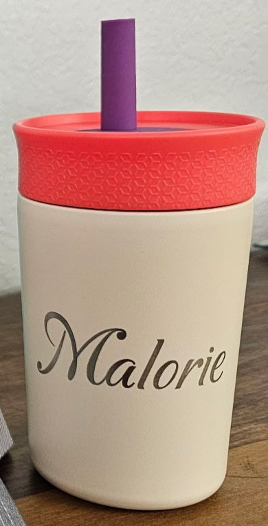 A cream-colored tumbler with the name "Malorie" engraved on it, featuring a red lid and a purple straw.