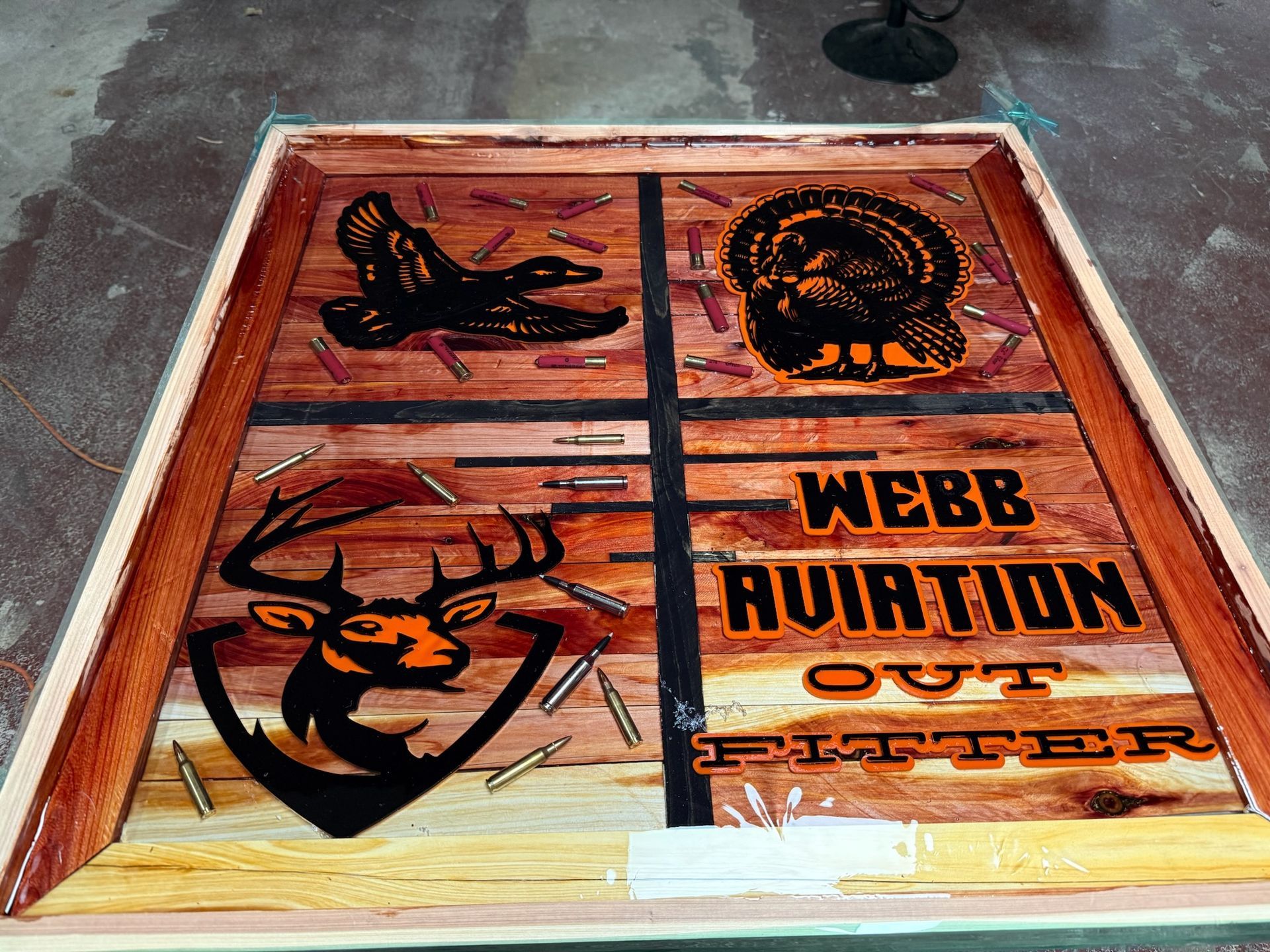 A wooden panel featuring etched wildlife images, shotgun shells, and the text 