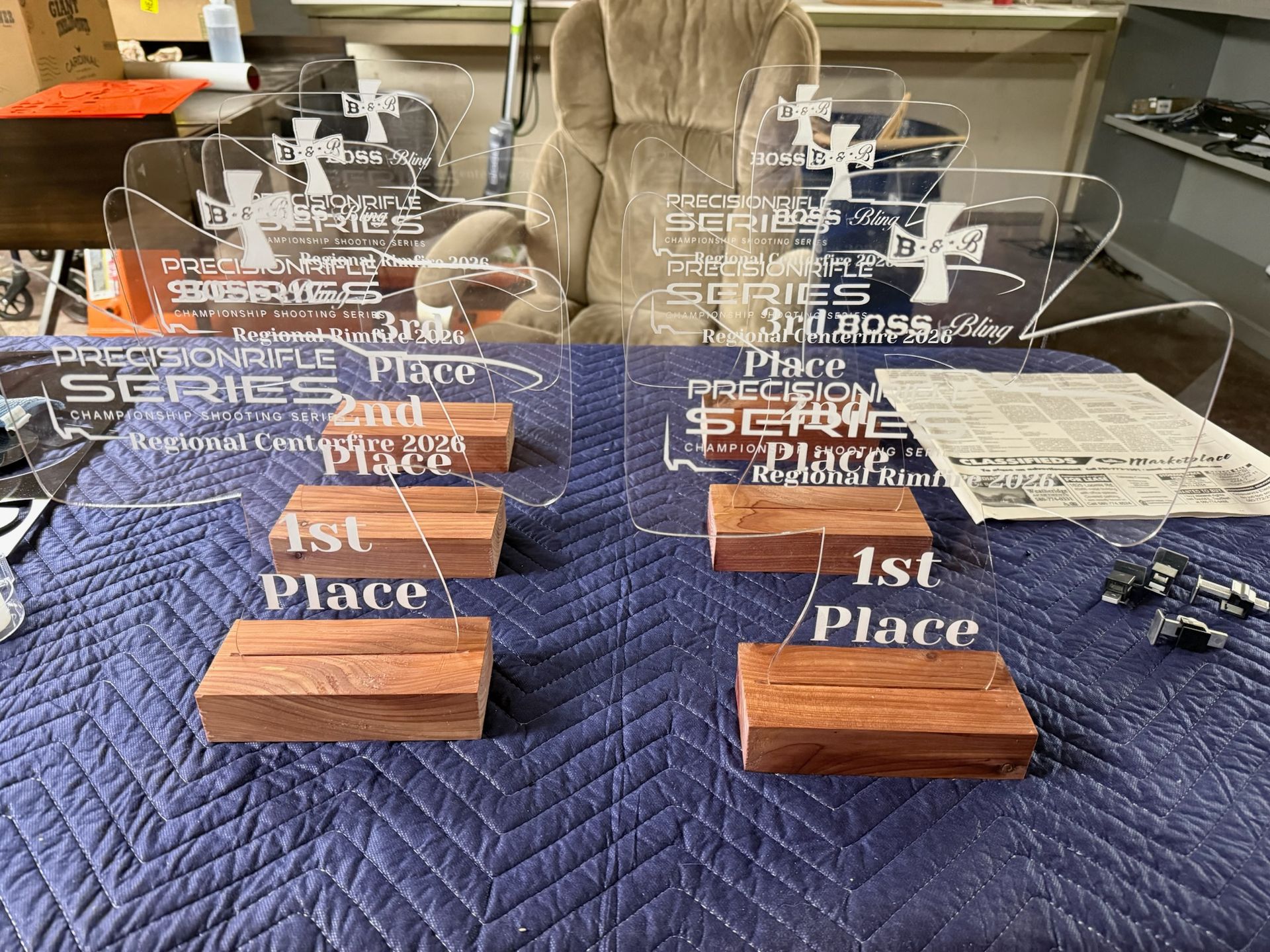 Trophies for a shooting competition on a blue table. Acrylic awards with wooden bases are set up.