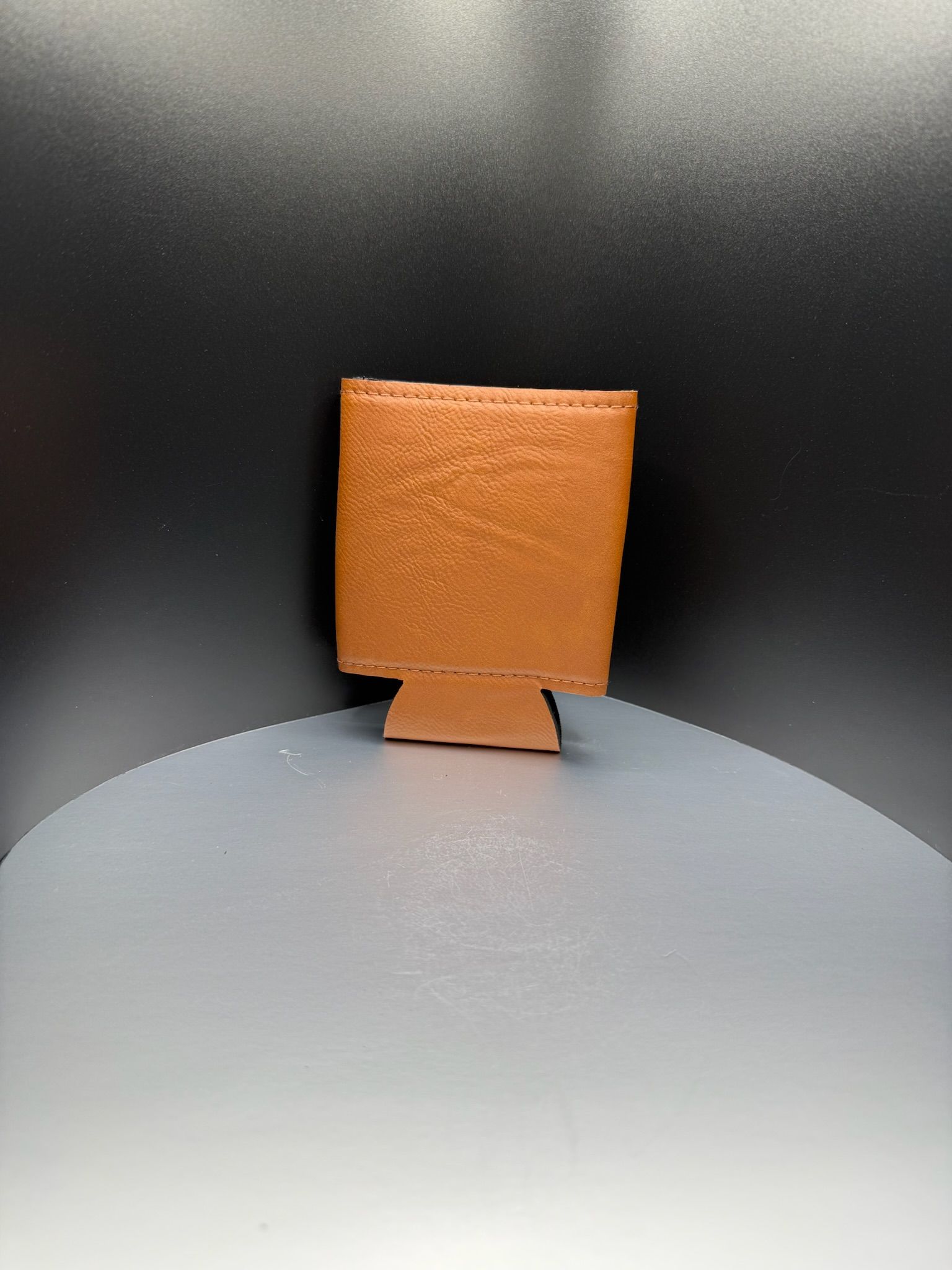 A plain, copper-colored beverage koozie standing upright against a dark gradient background.