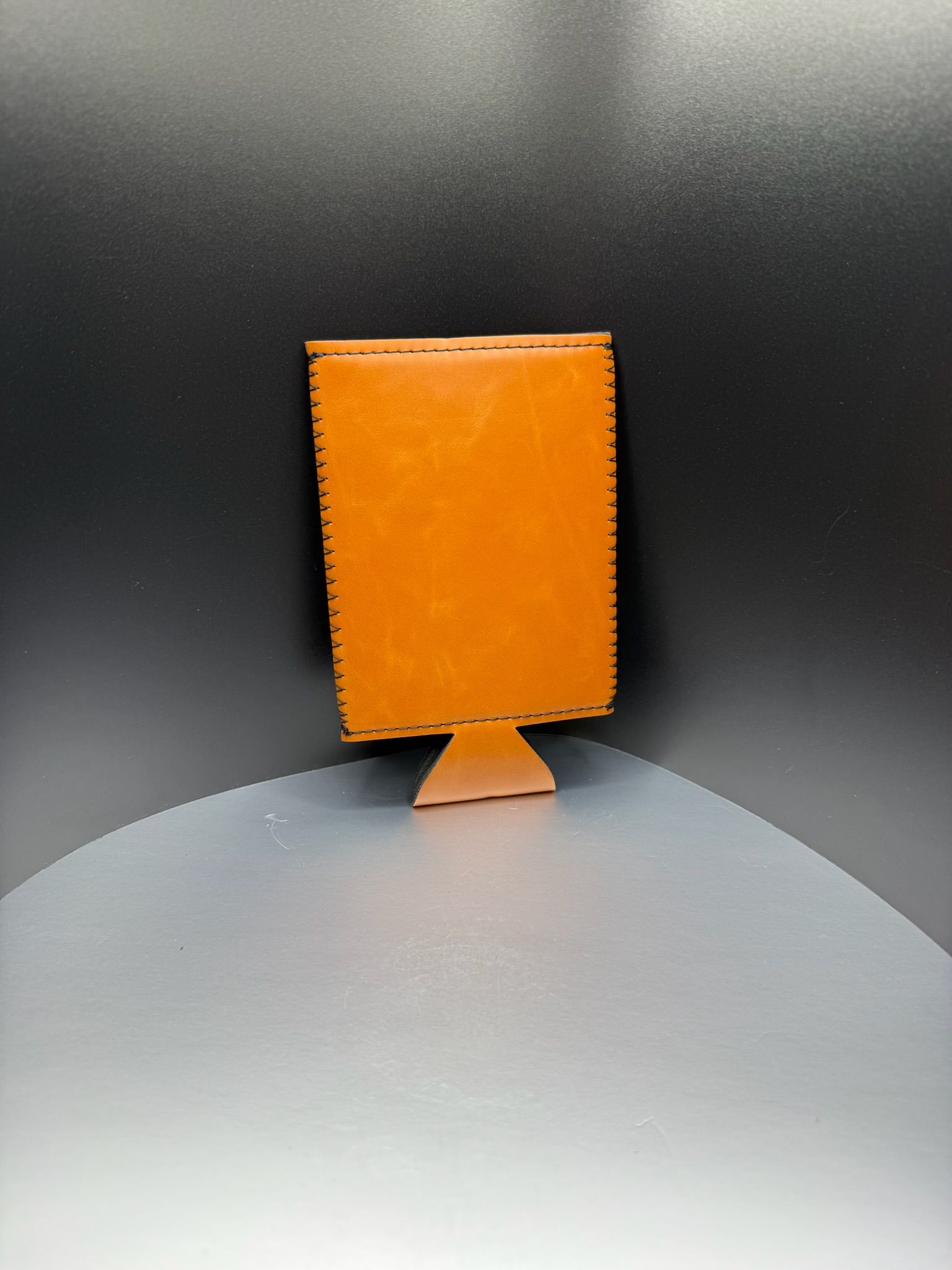 A plain, copper-colored beverage koozie standing upright against a dark gradient background.