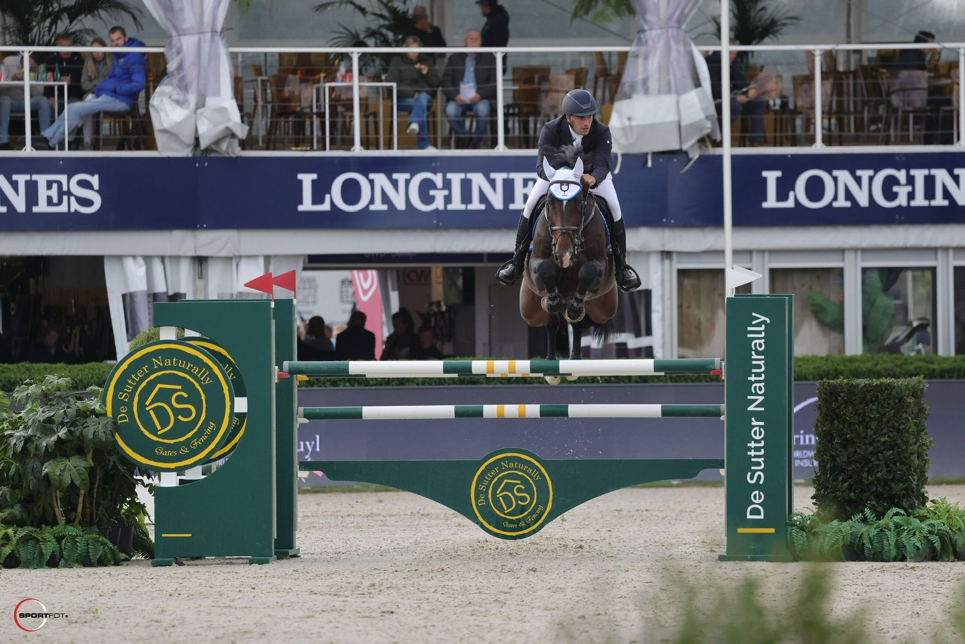 Donna su un cavallo marrone in un maneggio coperto, entrambi rivolti verso la telecamera.
