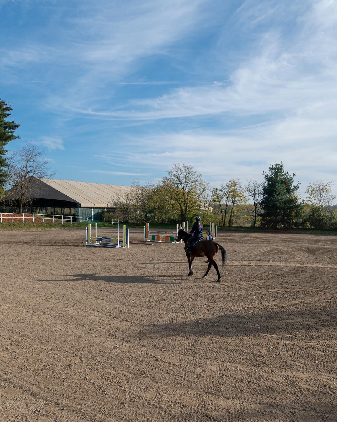 Maneggio coperto con ostacoli, coperto da un grande tetto e inondato di luce solare.