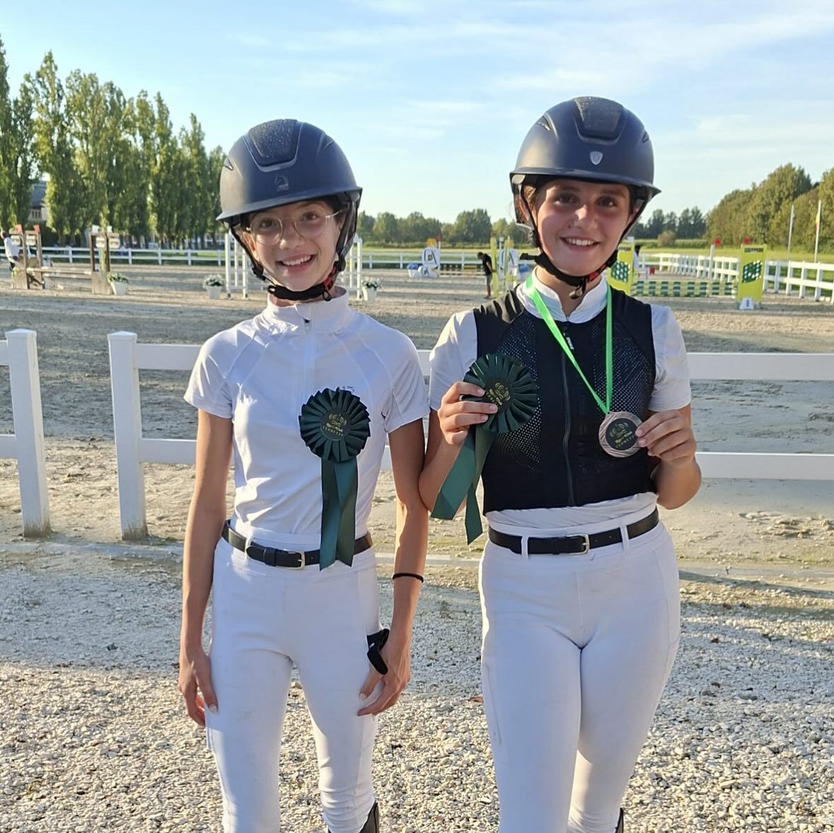 Due ragazze in tenuta da equitazione a uno spettacolo equestre, una delle quali tiene in mano una medaglia e un nastro.