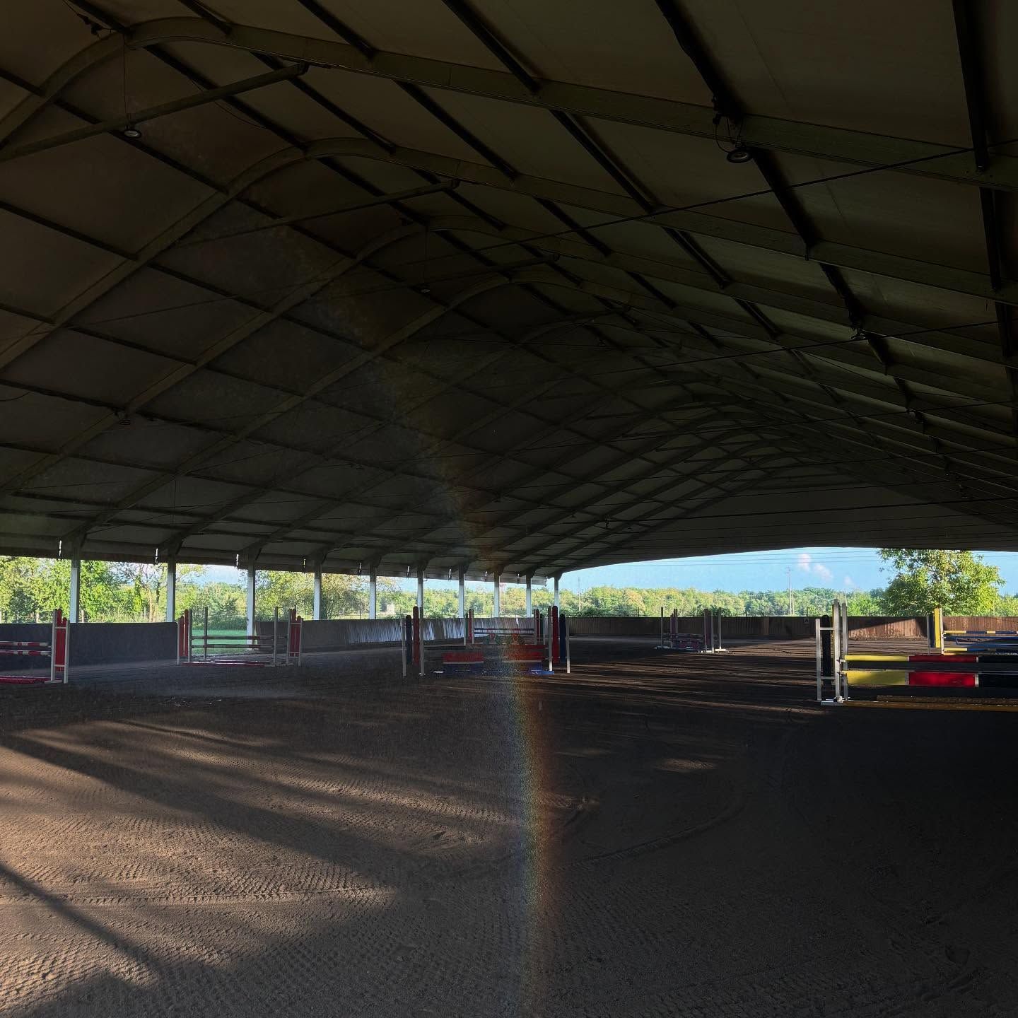 Maneggio coperto con ostacoli, coperto da un grande tetto e inondato di luce solare.