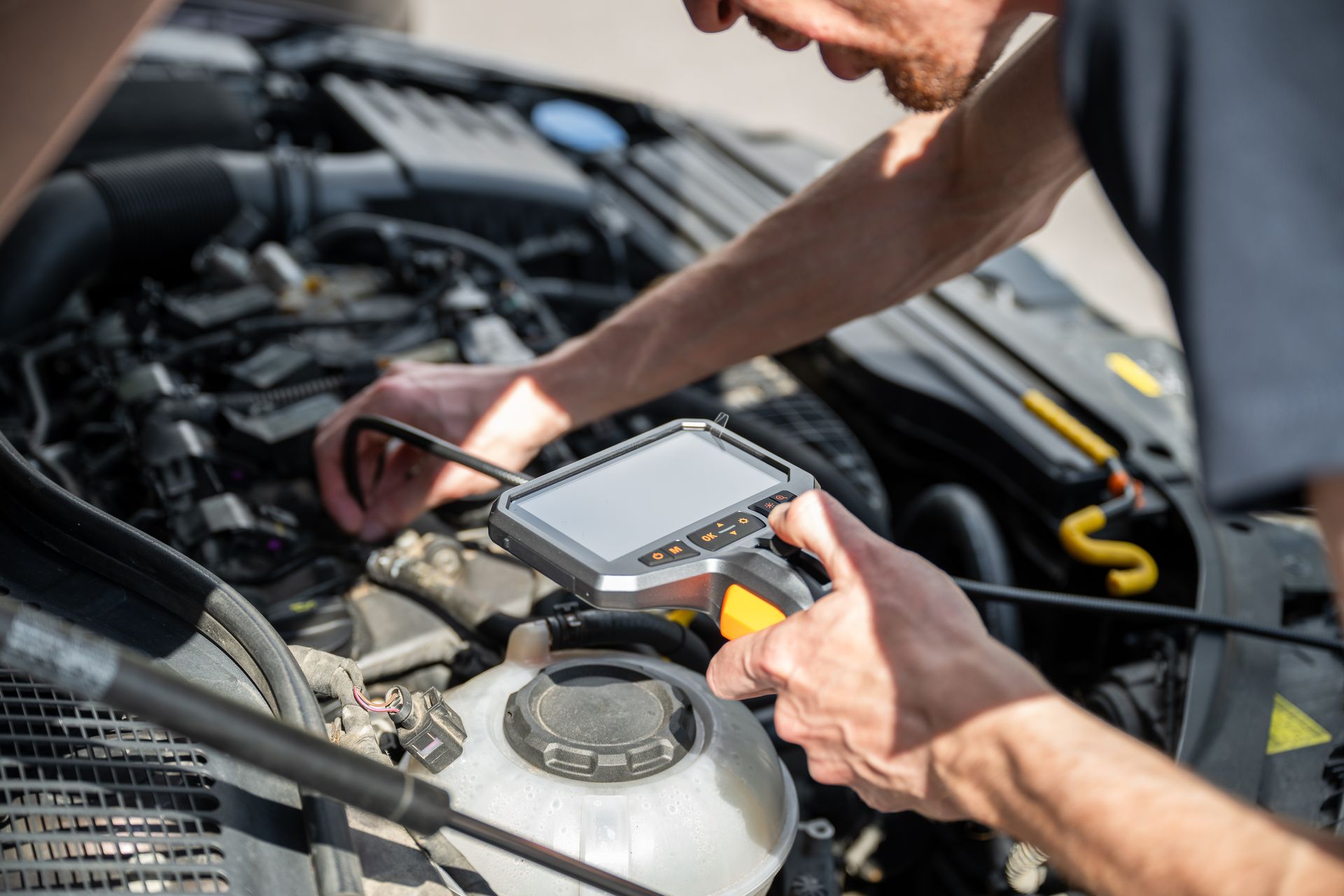 Person inspecting a car engine with an inspection camera.